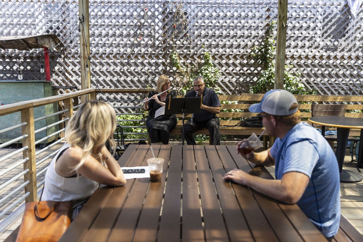 Sheila, left, and Dale West, right, listen to Janice MacDonald, center left, and Dileep Gangolli, center right, of the Chicago Sinfonietta play outside at the Back of the Yards Coffeehouse at 2059 W 47th St in Back of the Yards, Thursday, Aug. 5, 2021.